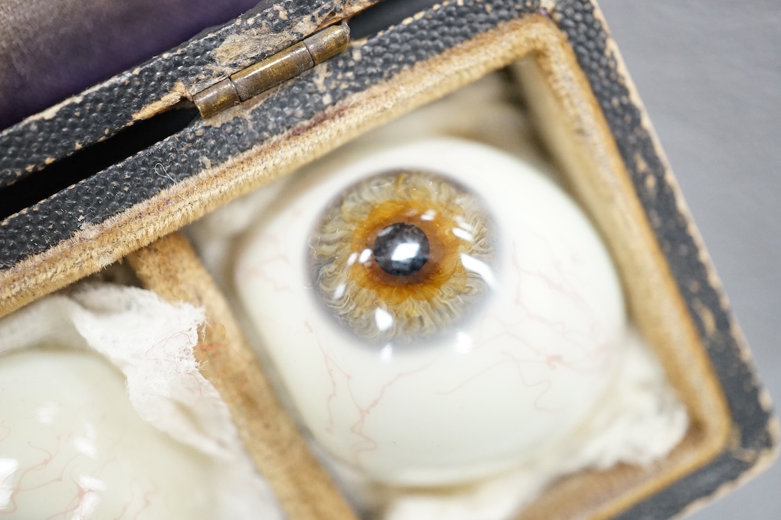 A late 19th century cased group of three prosthetic glass eyes